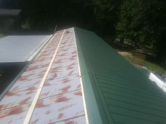 Old rusted panels beside newly installed green metal roofing — Wind Damage Roof Repair by Roofing Brothers in Rohrersville