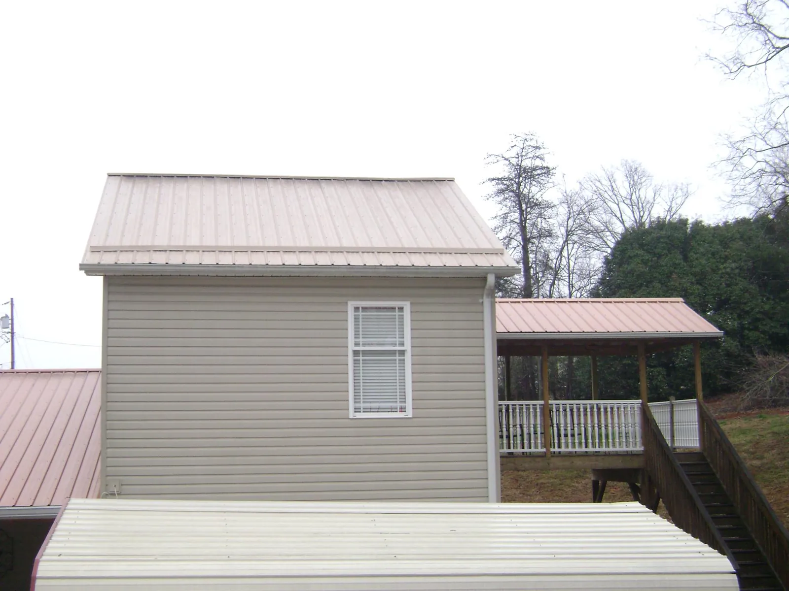 Tan metal roofs on a two story addition and attached porch, from a Roof Replacement job in Rohrersville