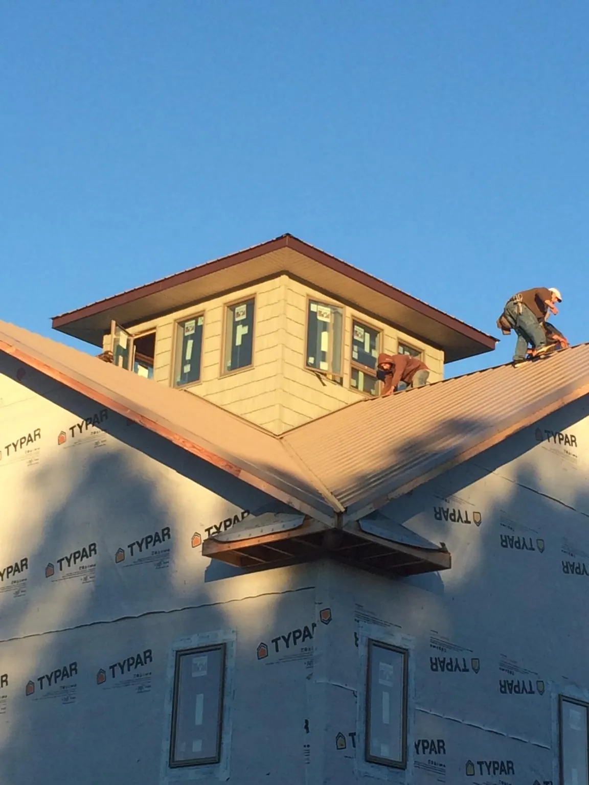 Roofers working around a rooftop cupola on a new metal roof at sunset — Roof Waterproofing in Rohrersville by Roofing Brothers